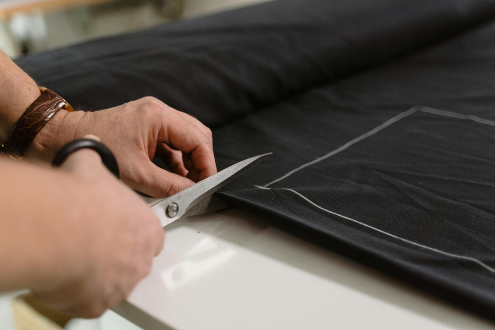 Master tailor cutting fabric with chalk markings — expert alterations and repairs at Outfit Tailor Koh Samui