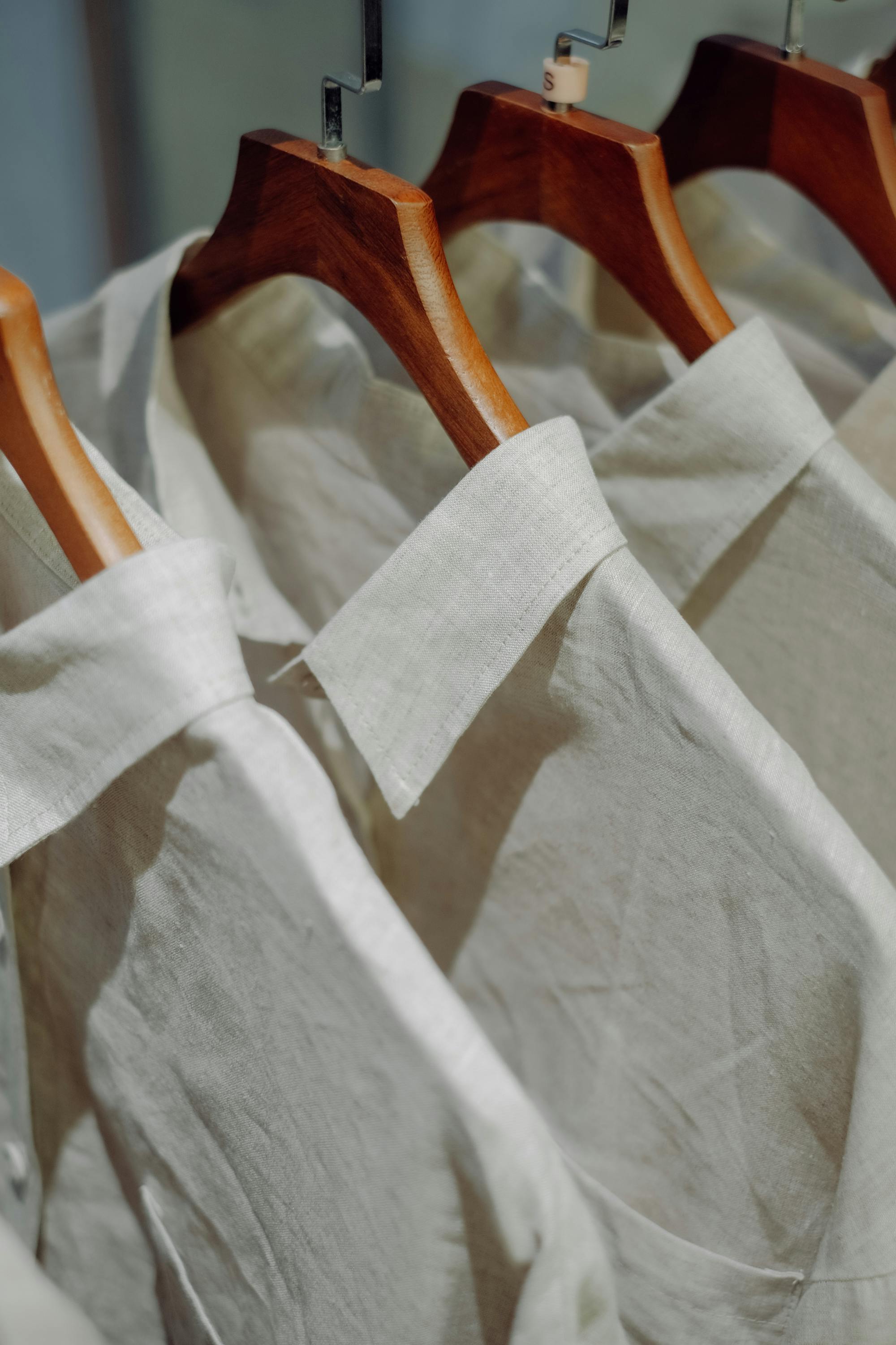 Custom dress shirts handcrafted in linen and cotton on wooden hangers — Outfit Tailor Koh Samui
